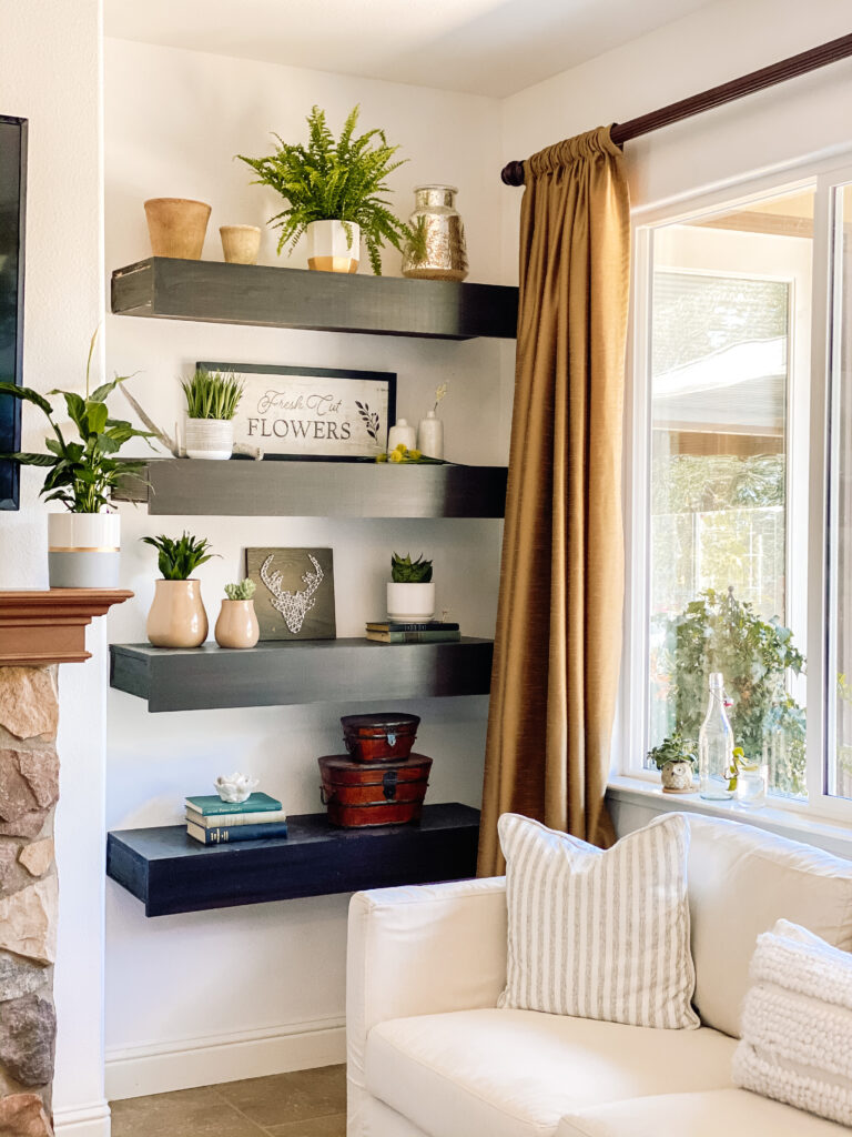 Floating shelves next to fireplace, decorated with plants, vases and other objects that floating shelves fireplace areas need for balanced shelf decorating.