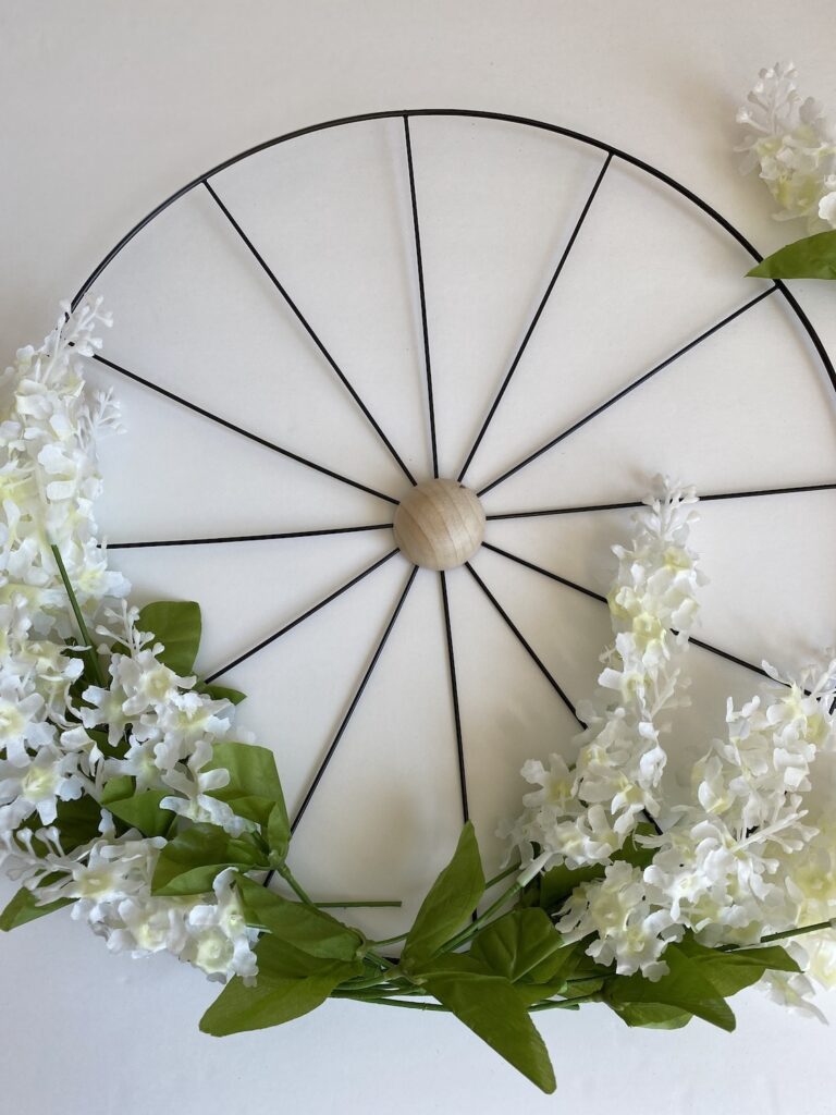 Showing how to make a Dollar Tree bicycle or wagon wheel wreath with flowers