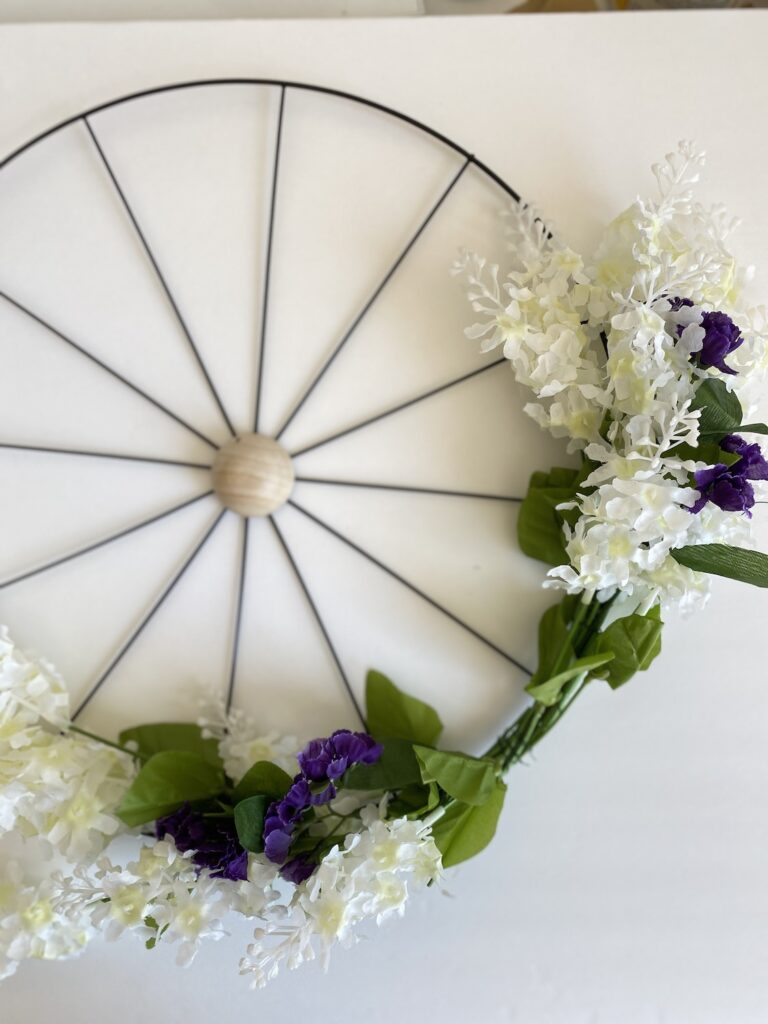 showing more steps for how to make a Bicycle or wagon wheel wreath with purple and white flowers