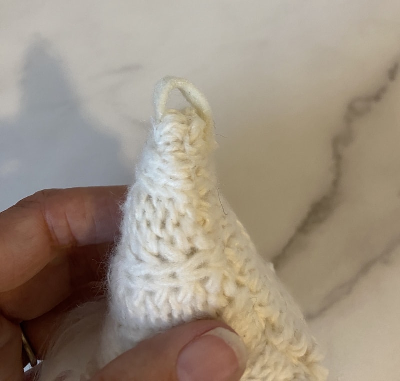 making a gnome garland and gluing a strip of felt to the top of the hat for hanging