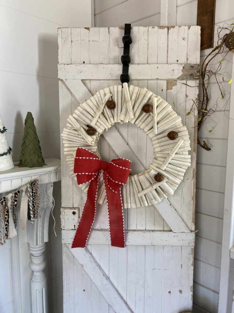 Book Page Wreath DIY with red bow and bells hanging on a door