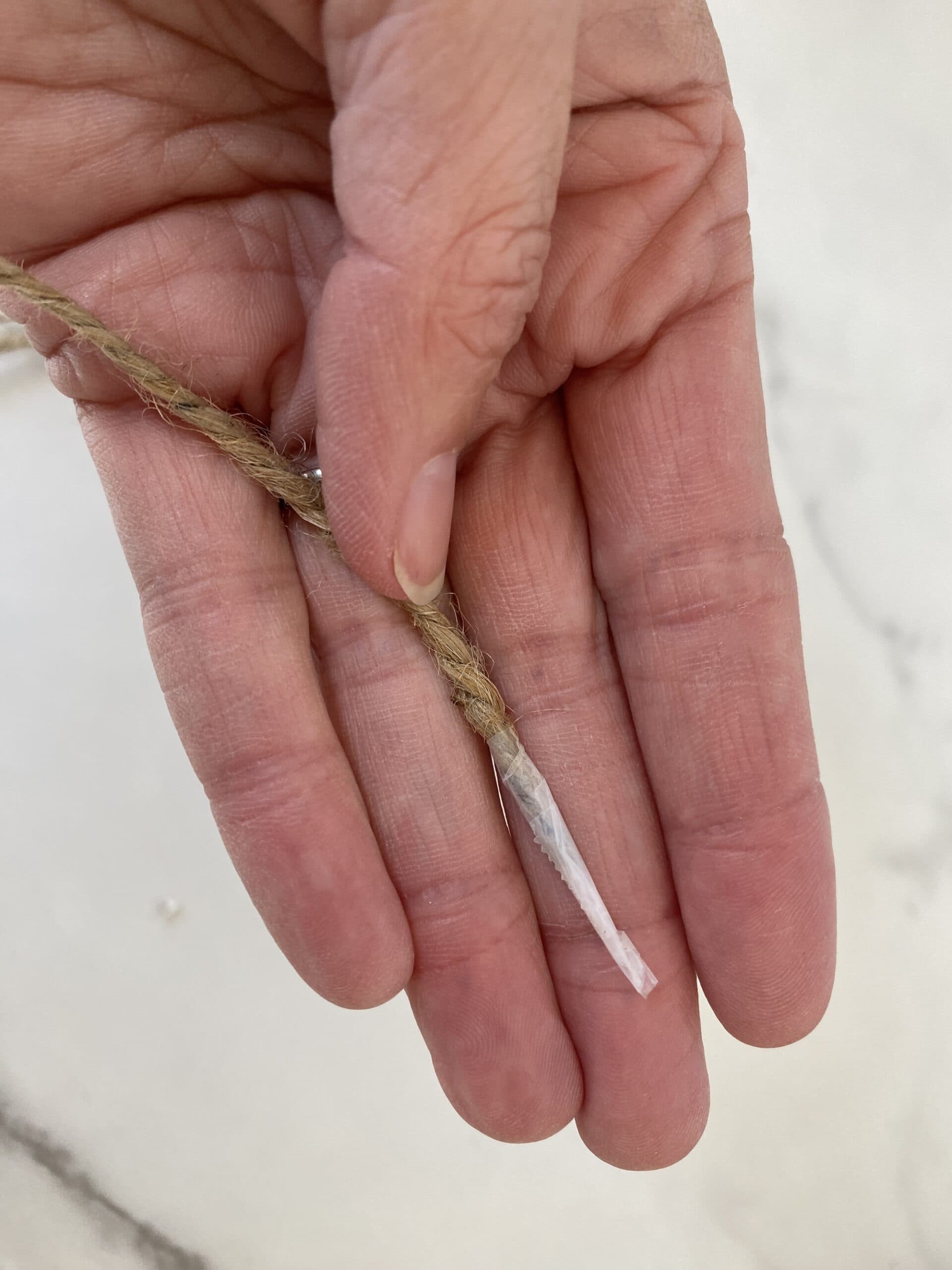 Showing how to string beads on a garland using tape on the end as a needle